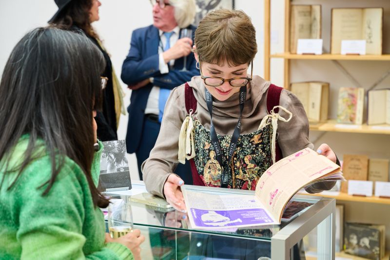 Smiling book dealer turning the page of a book at Firsts London